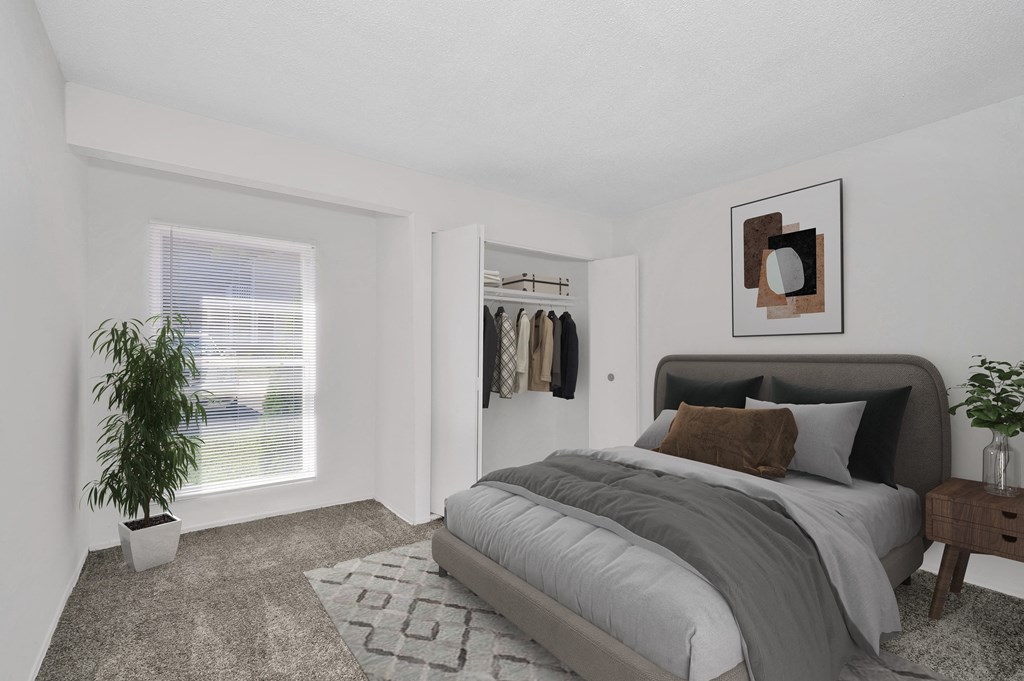 a bedroom with a large window and a bed with a grey comforter