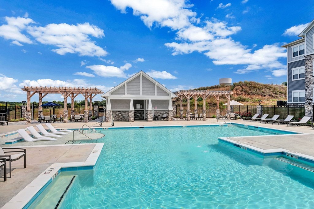 a swimming pool with chairs and a building in the background