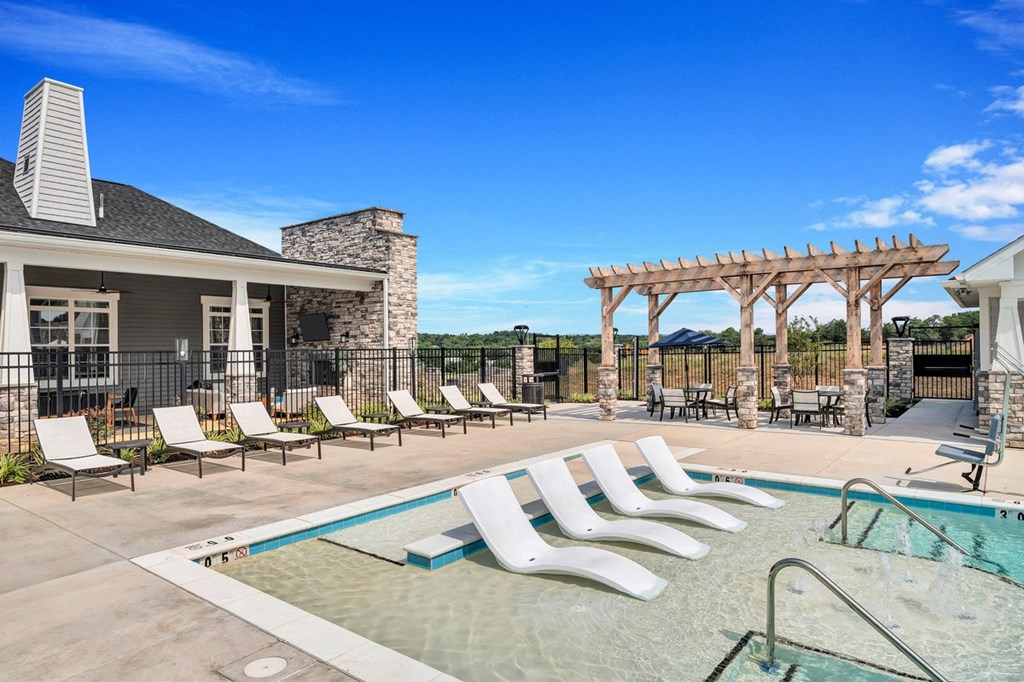 a swimming pool with chaise lounge chairs and a house in the background