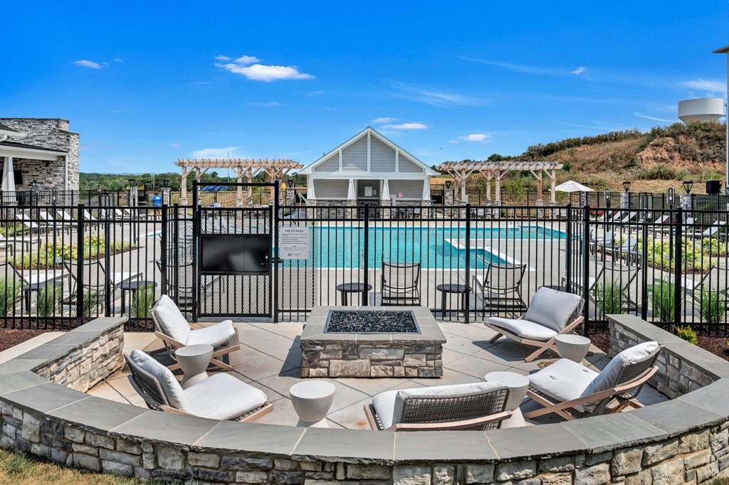 an outdoor patio with chairs and a fire pit and a swimming pool