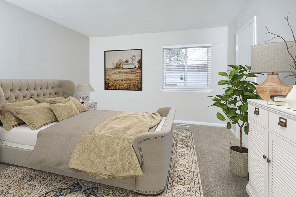 a bedroom with a bed and a chair and a plant