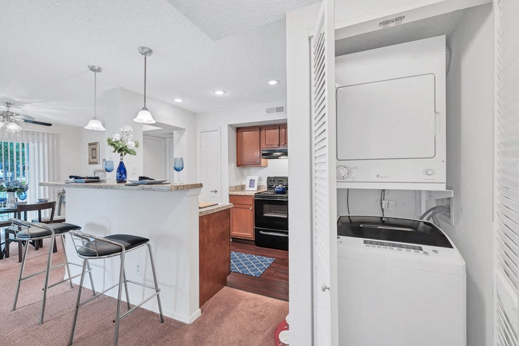 a white kitchen with a bar and a dining room