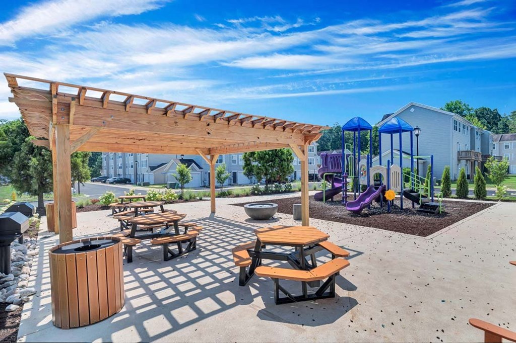a picnic area with benches and a playground in the background