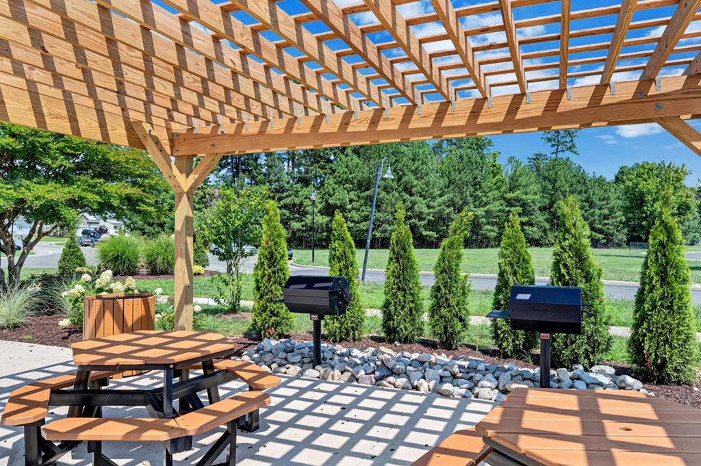 a wooden pergola with a table and benches under it