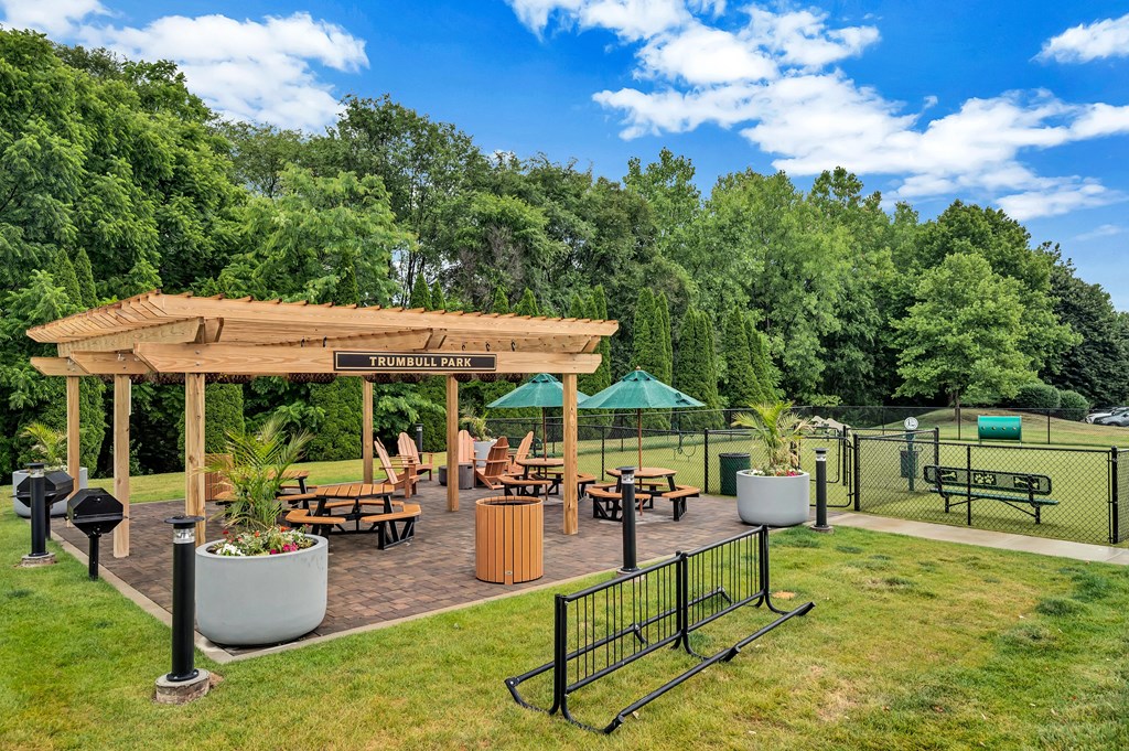 a pavilion with a seating area and a dog park in the background