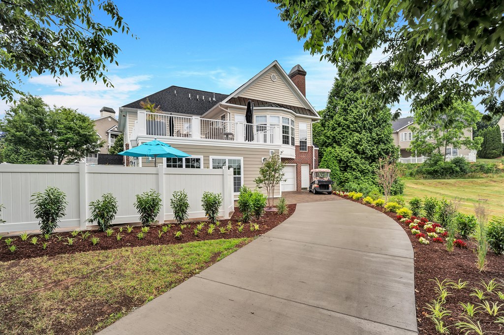 a large white house with a gray roof and a gray sidewalk in front of it