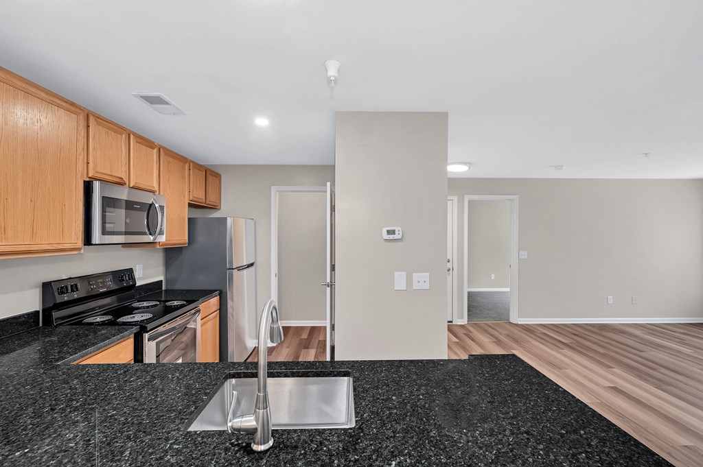 A kitchen with a black granite countertop and wooden cabinets.