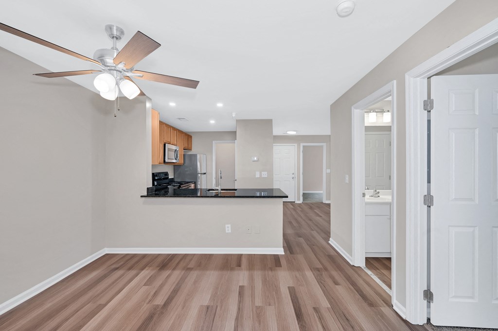 A kitchen with a fan and wooden floors.