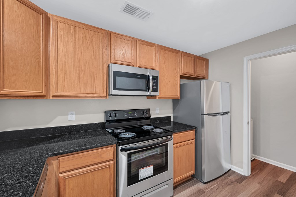 A kitchen with wooden cabinets and a black countertop.
