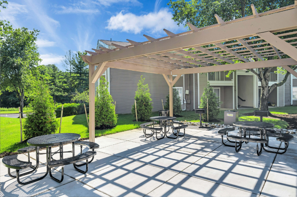 a patio with tables and chairs under a wooden pergola