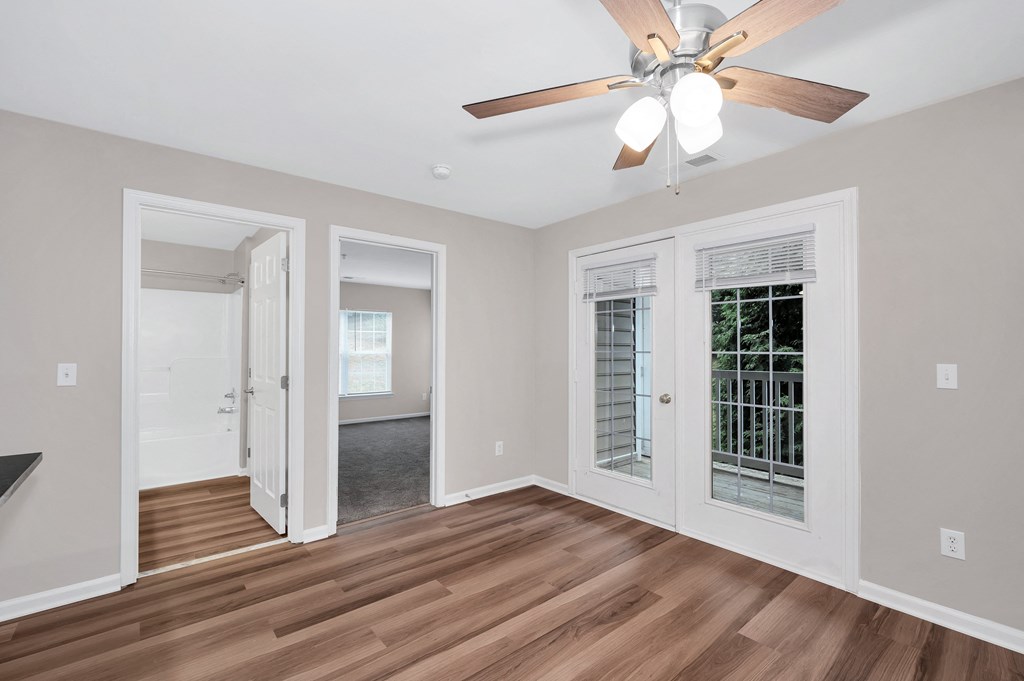 A room with a ceiling fan and wooden floors.