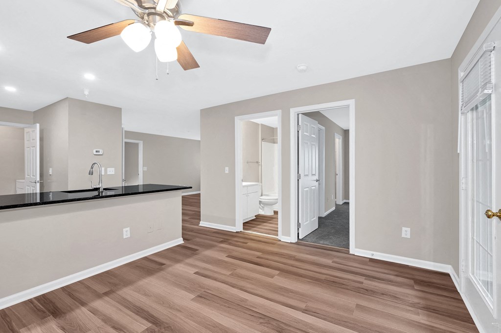 A spacious kitchen with a ceiling fan and wooden flooring.