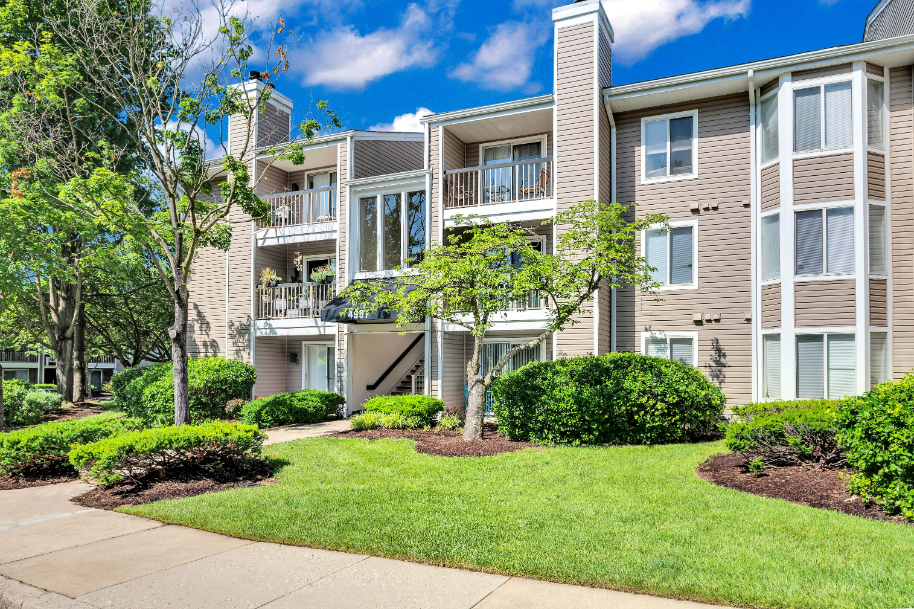 an apartment building with a lawn and trees in front of it