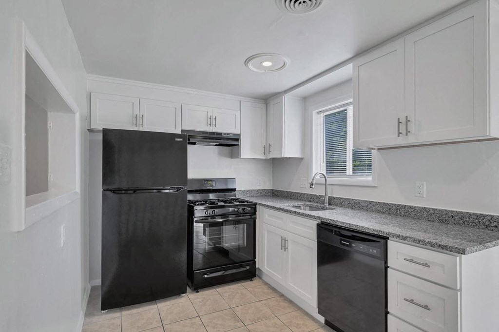 a kitchen with white cabinets and black appliances