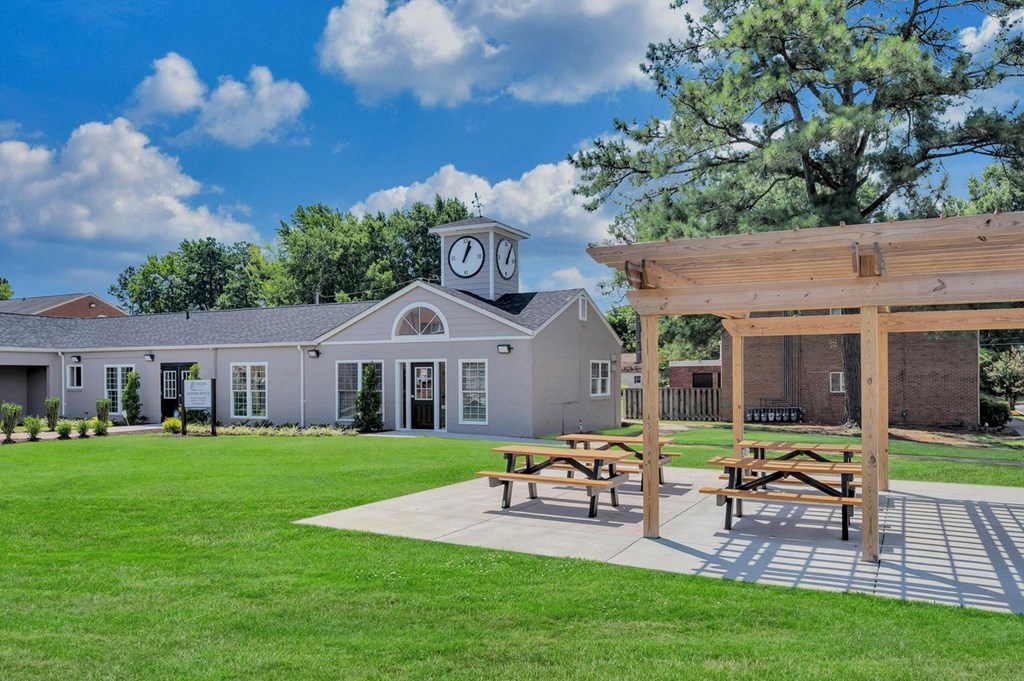 a pavilion with picnic tables and a building with a clock on it