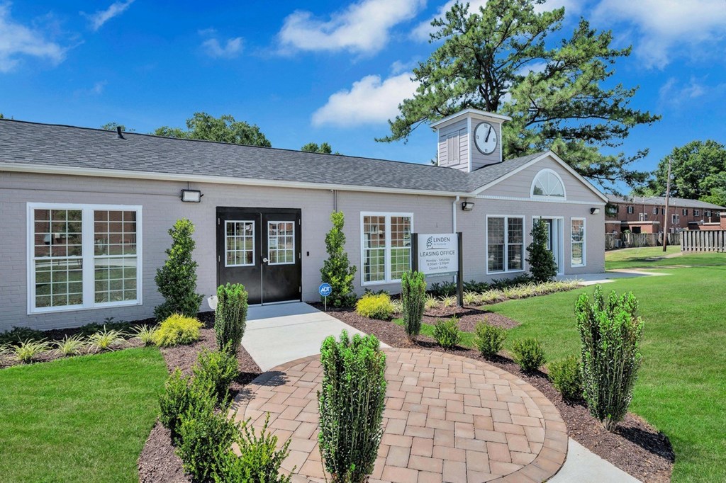 the front of a white building with a clock on the roof and a walkway