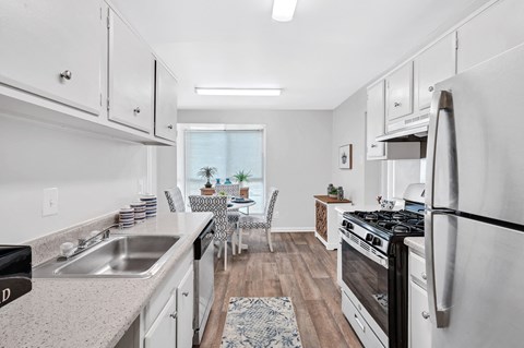 an open kitchen and dining room with white cabinets and stainless steel appliances