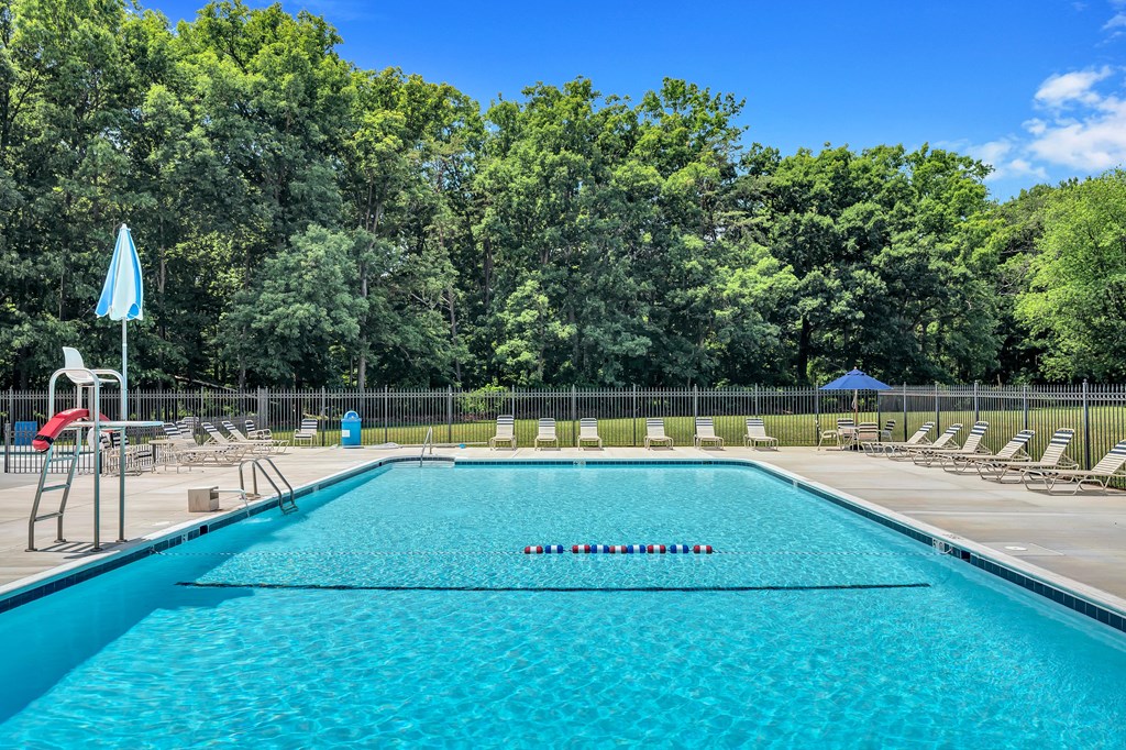 a swimming pool with chaise lounge chairs and trees in the background