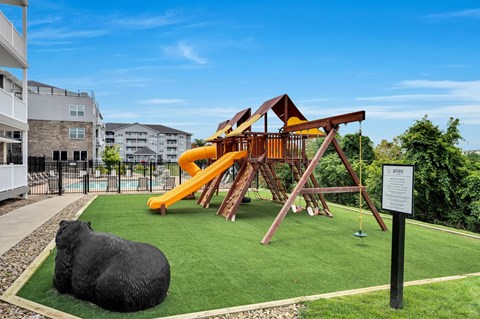 a playground with a swing set and a bull statue on the grass