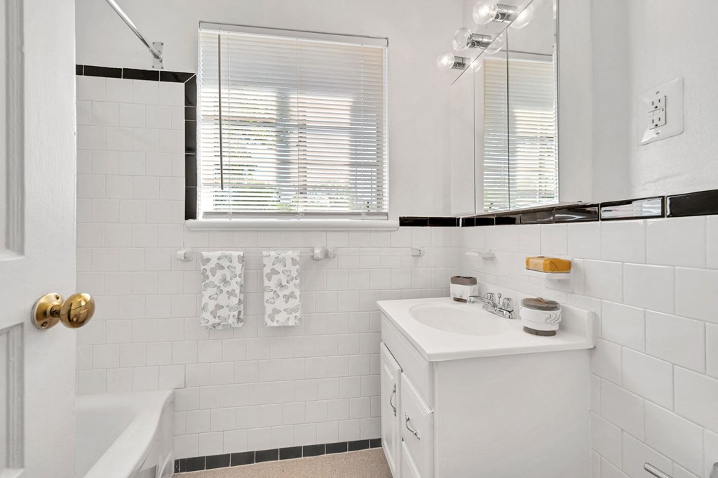 a white bathroom with a sink and a bath tub