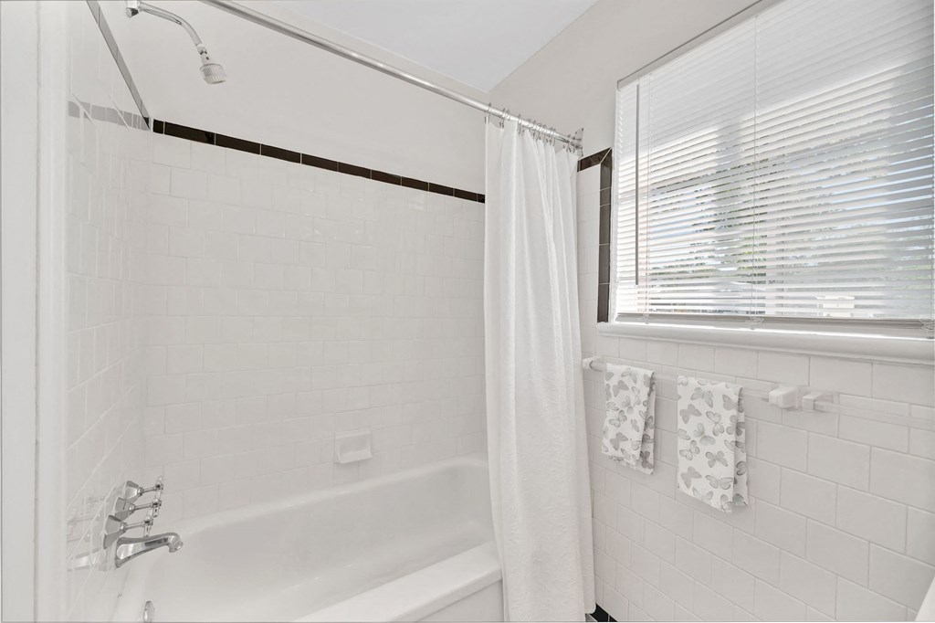 a white bathroom with a tub and a window