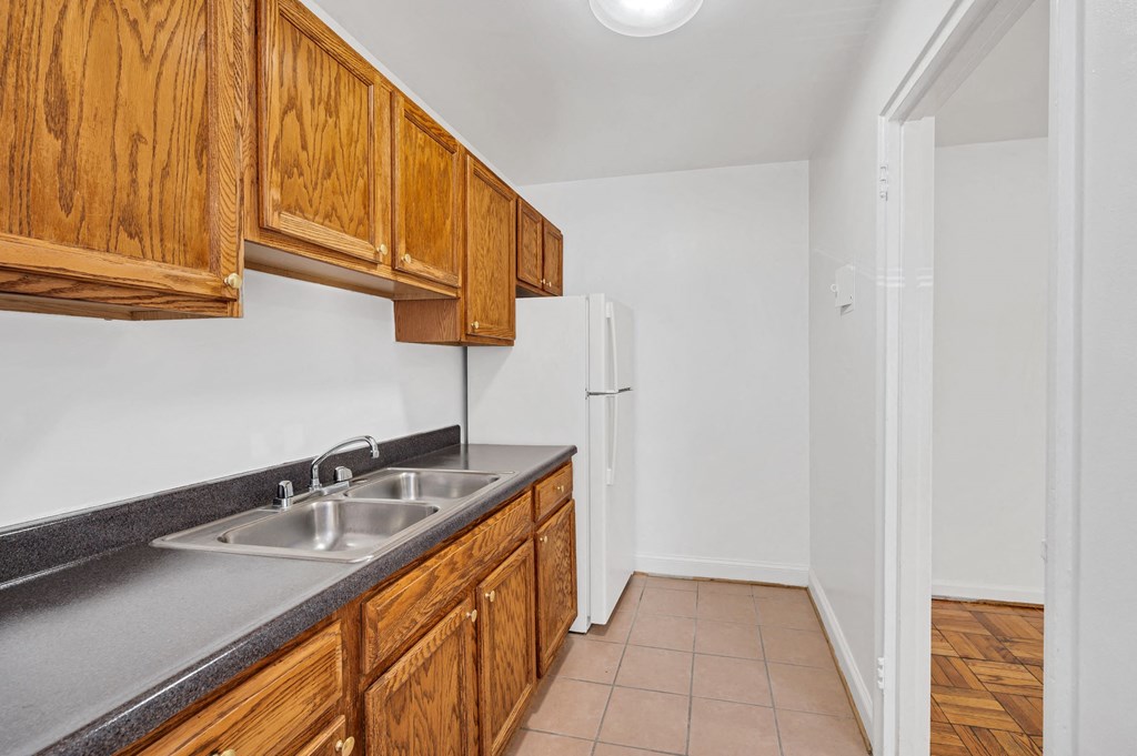 a kitchen with a sink and wooden cabinets and a refrigerator