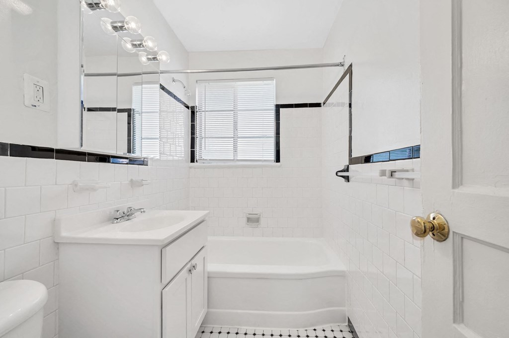 a white bathroom with a tub and a sink and a mirror