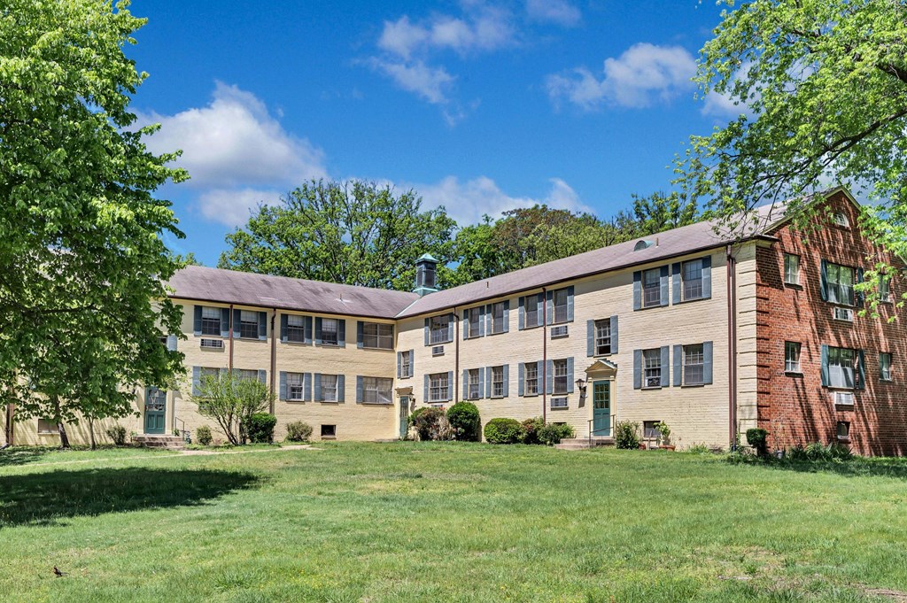 a large brick apartment building with green grass and trees