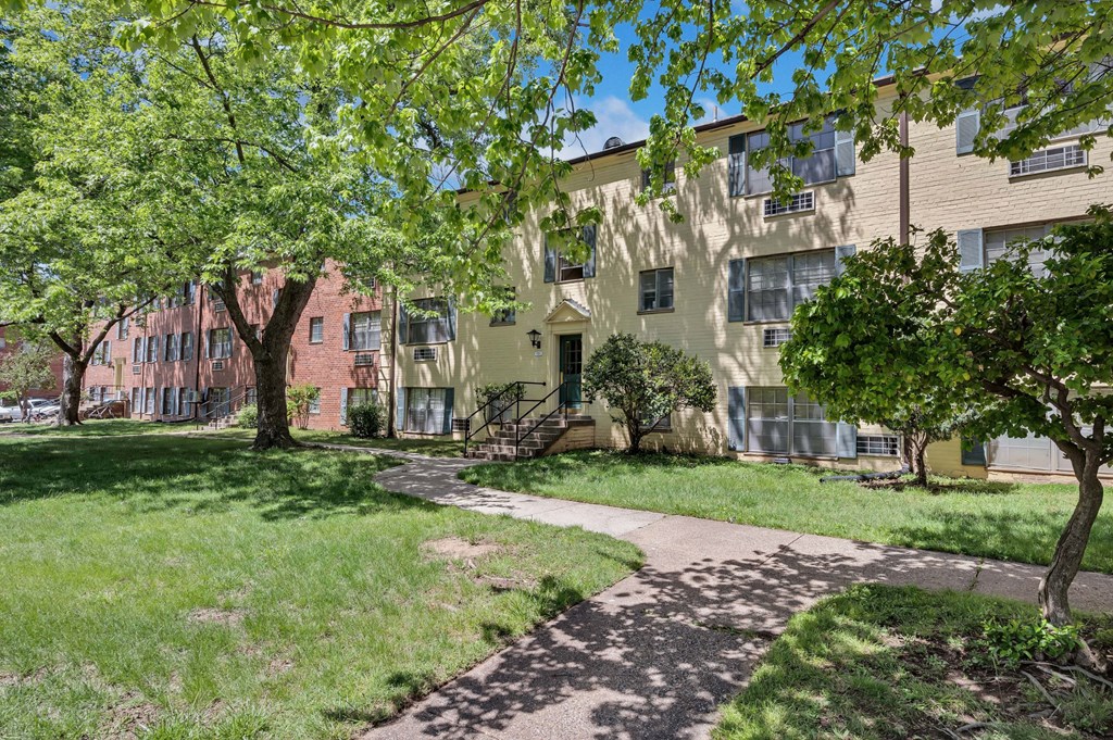 an apartment building with a sidewalk and trees