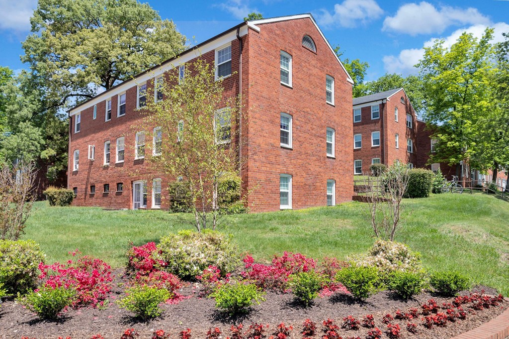 the front of a brick apartment building with a landscaped garden