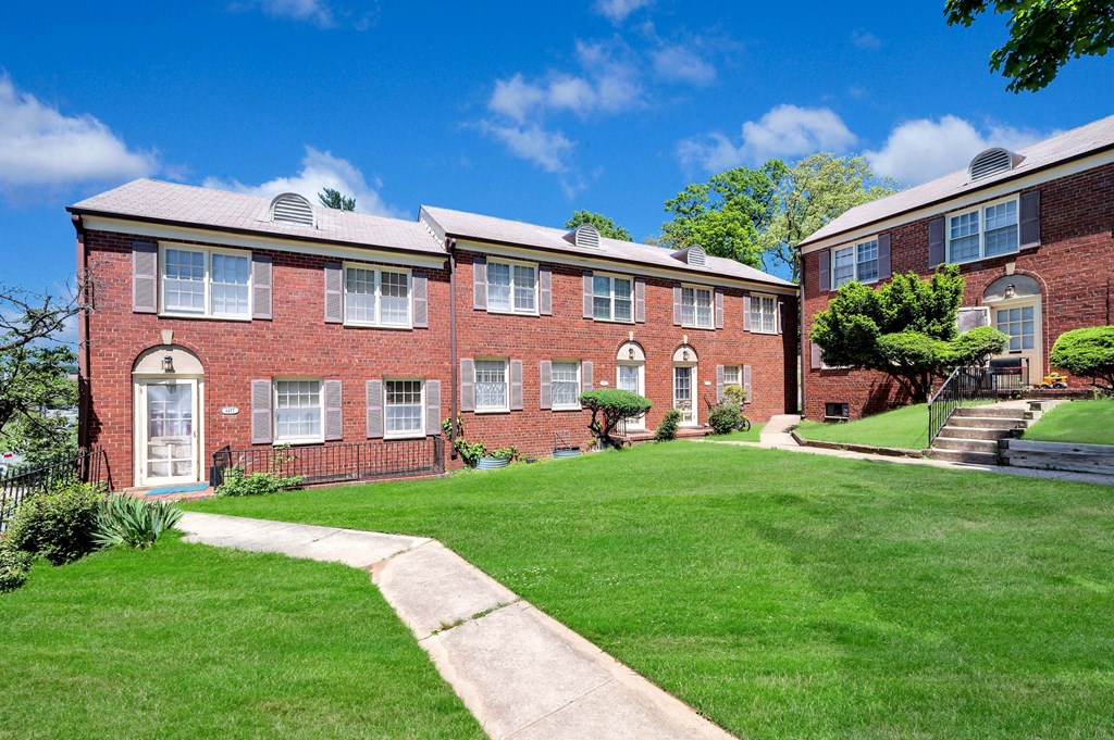 a brick apartment building with a lawn in front of it