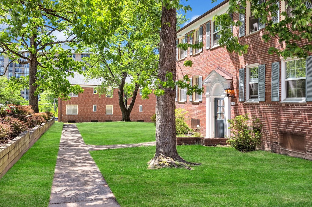 exterior view of a brick apartment building with a lawn and trees