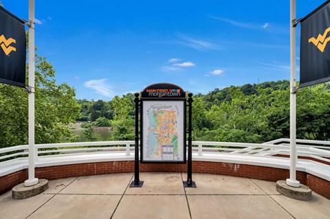 a sign with a map on a bridge overlooking a river