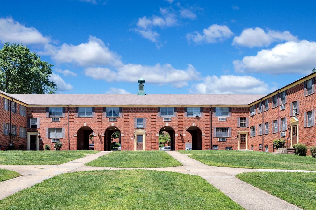 a brick building with green grass and a blue sky