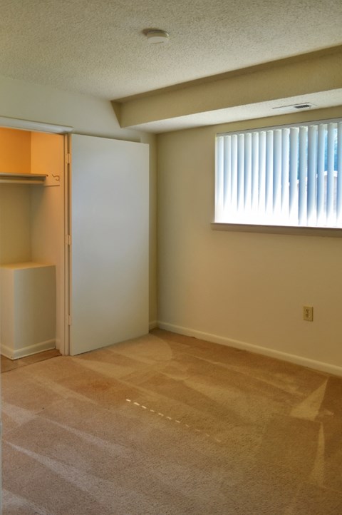 an empty living room with a closet and a window