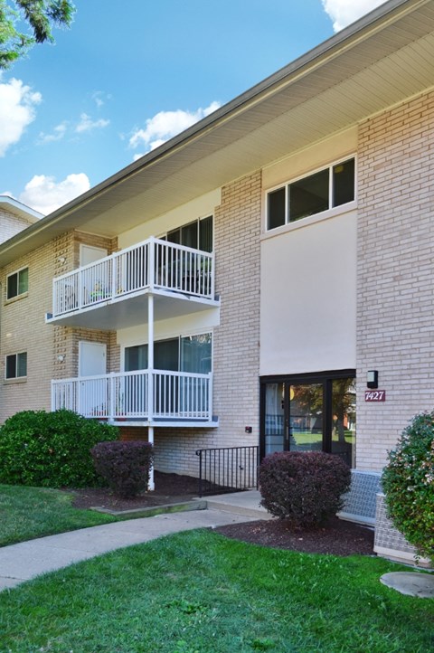 an exterior view of a brick building with a balcony and a sidewalk
