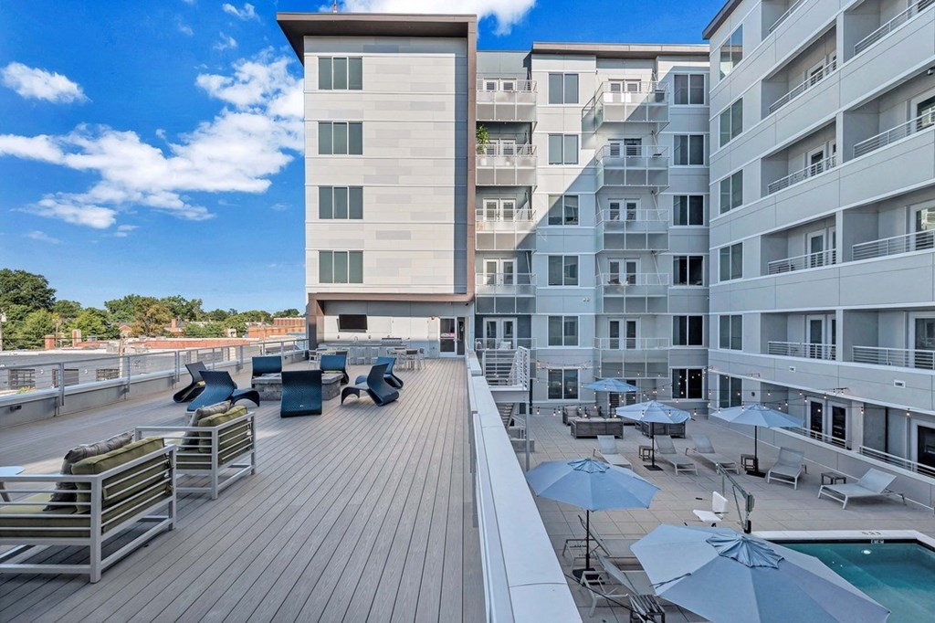 a large balcony with a pool and chairs and umbrellas