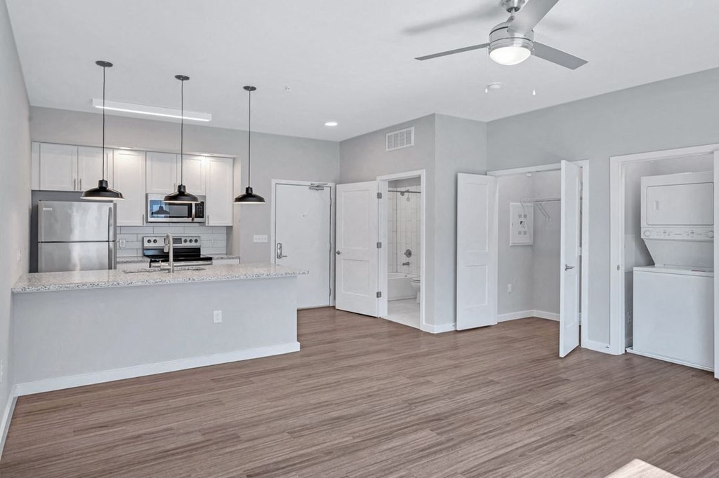 an open kitchen and living room with a counter top and a refrigerator