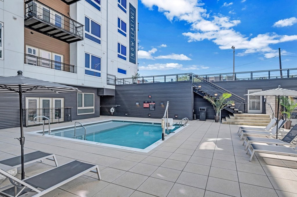 a pool with lounge chairs and a building in the background