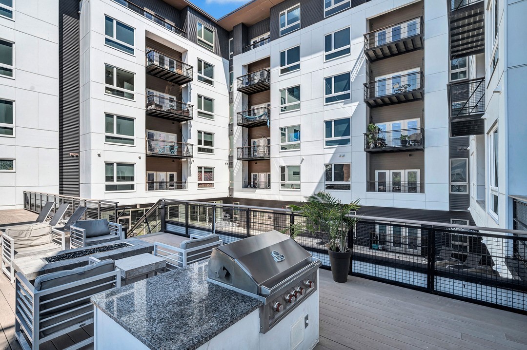 an outdoor patio with a grill and an apartment building in the background