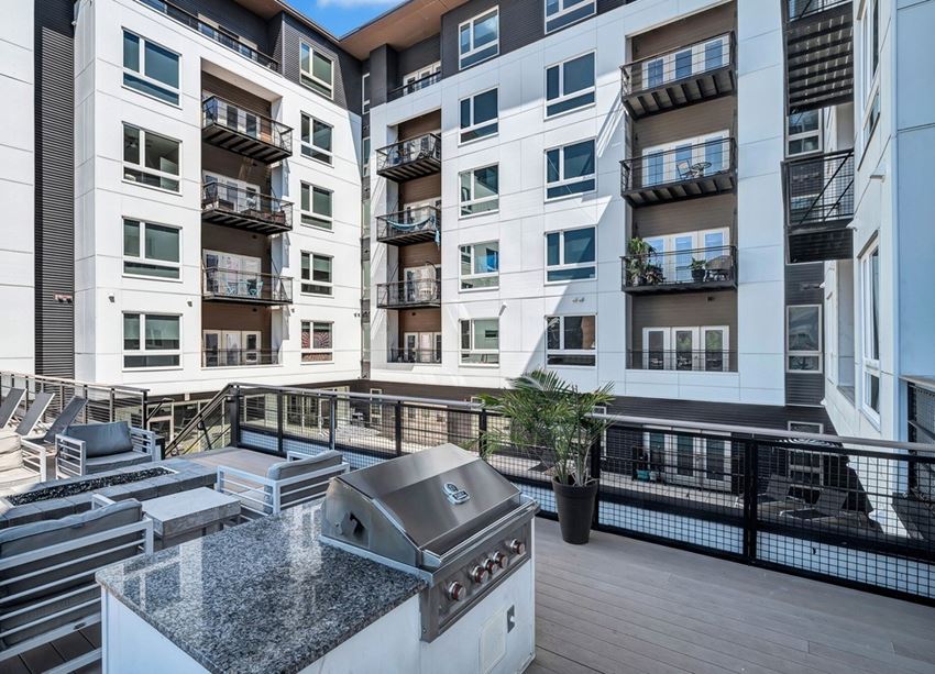 an outdoor patio with a grill and an apartment building in the background