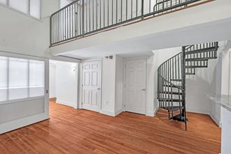 A spiral staircase is highlighted off the living room of a Richmond loft apartment with original wood floors.