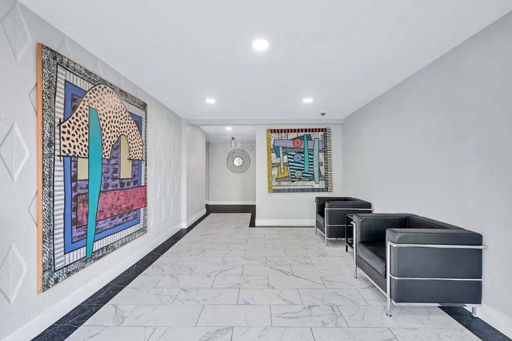 a lobby with two chairs and a painting on the wall