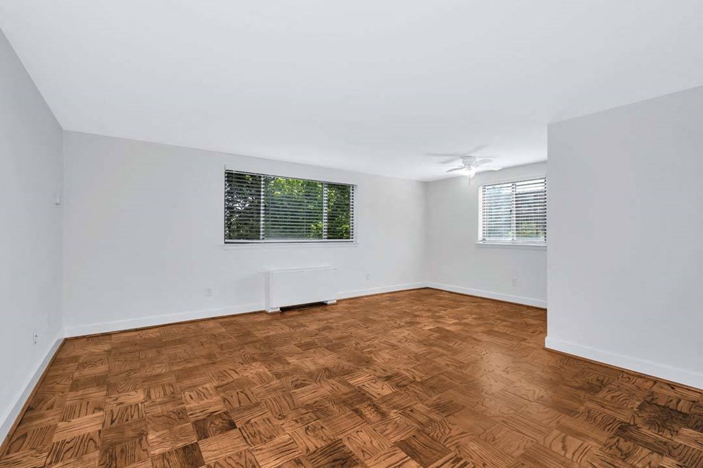 a bedroom with two windows and a hardwood floor