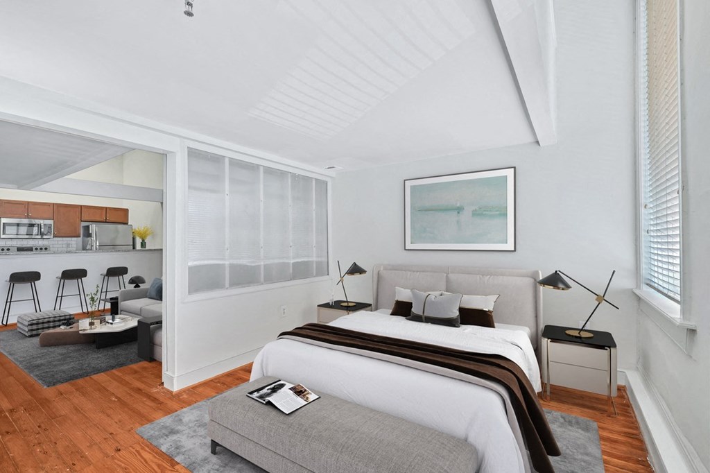 a bedroom with a bed and a kitchen in the background