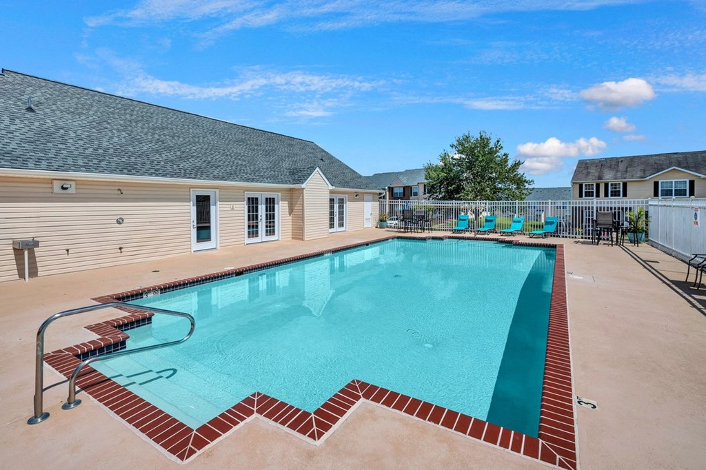 our resort style swimming pool is next to our building with chairs and a house