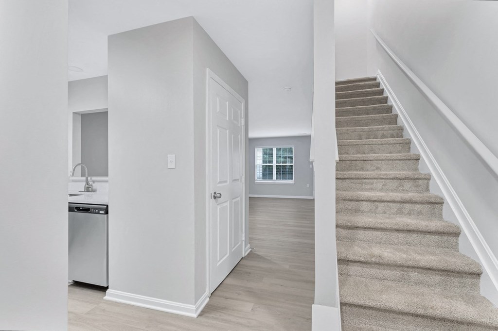 a renovated living room and staircase with a kitchen in a house