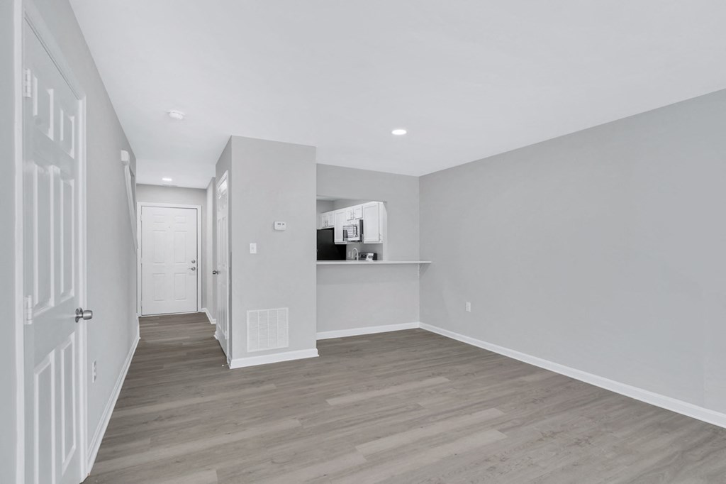 a renovated living room and hallway with white walls and wood floors
