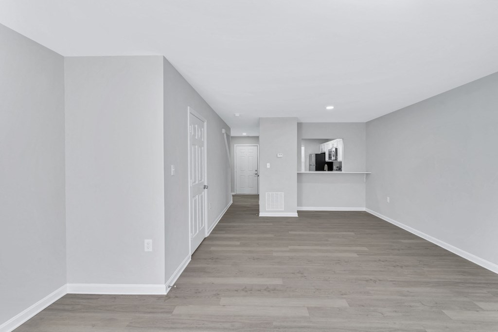 a renovated living room and hallway with white walls and wood floors