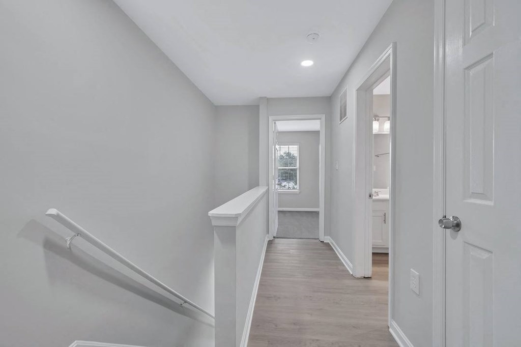 a white hallway with stairs and a door to a bathroom